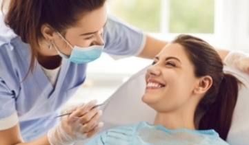 Dentist performing a dental checkup on a smiling female patient in clinic