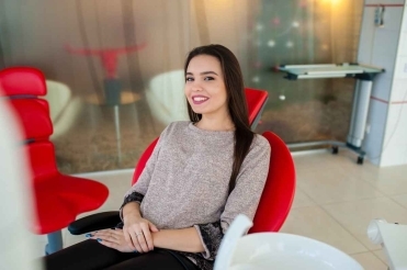 Smiling woman sitting in a dental chair during an emergency dentistry consultation in a modern clinic