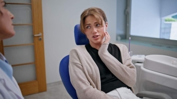 Adult patient holding her jaw while speaking with a dentist during a family dental consultation