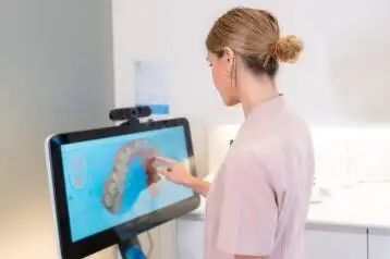 Dentist reviewing a 3D dental scan on a monitor.