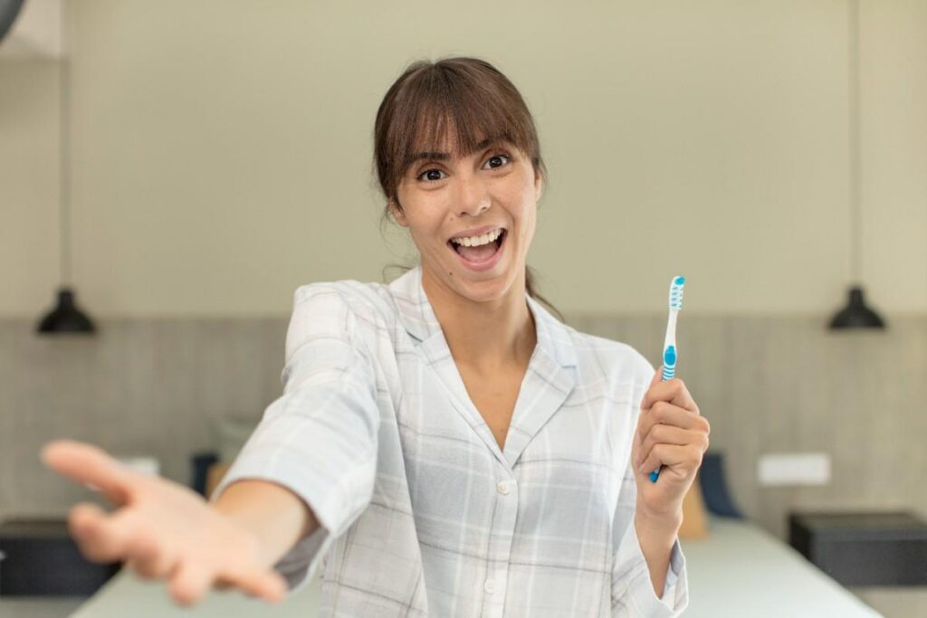 Woman holding a toothbrush and smiling, representing healthy teeth after root canal treatment