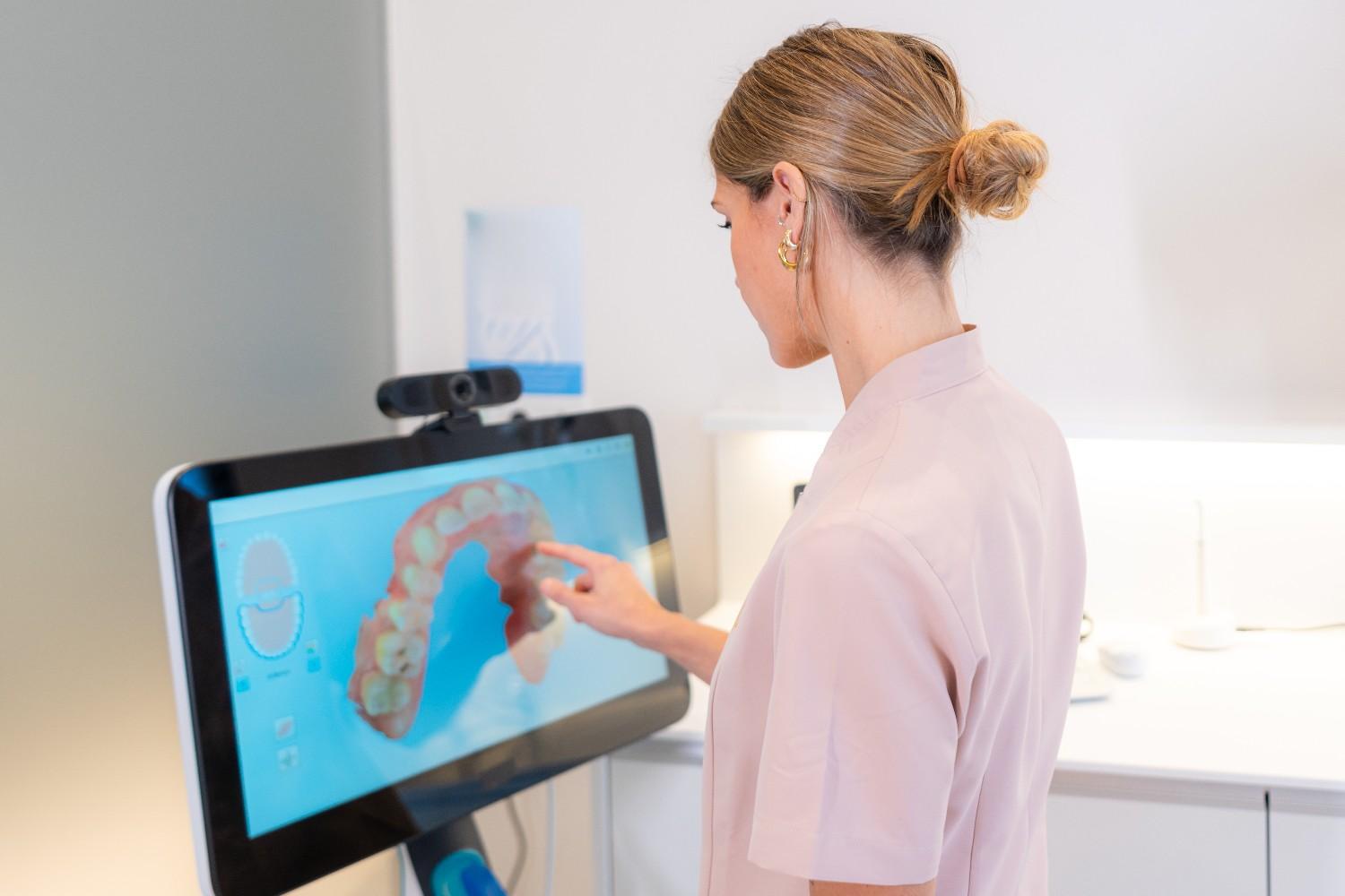 Dentist reviewing a 3D dental scan on a monitor.