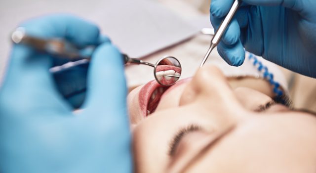 woman opening her mouth wide during inspectionwoman opening her mouth wide during inspection for dental inlays and onlays at the dentist's office