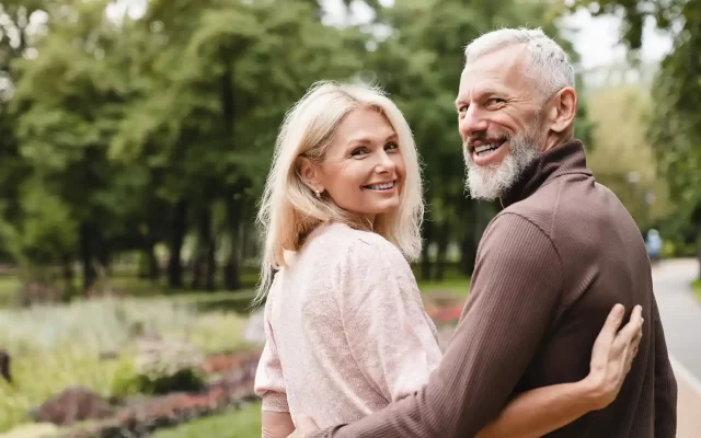 Older Man and Woman On a Walk Outside Smiling.